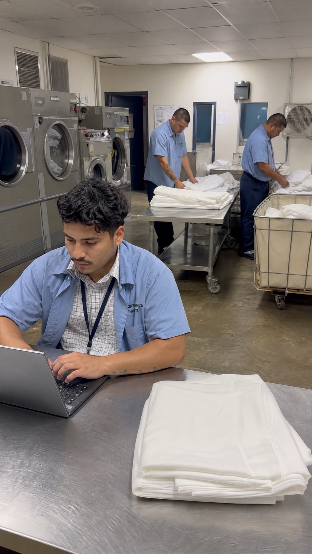 Approved wider scene of an attendee working on a laptop in the prison laundry