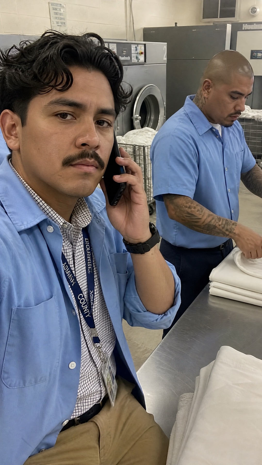 Initial close-up of an attendee making a phone call in the prison laundry
